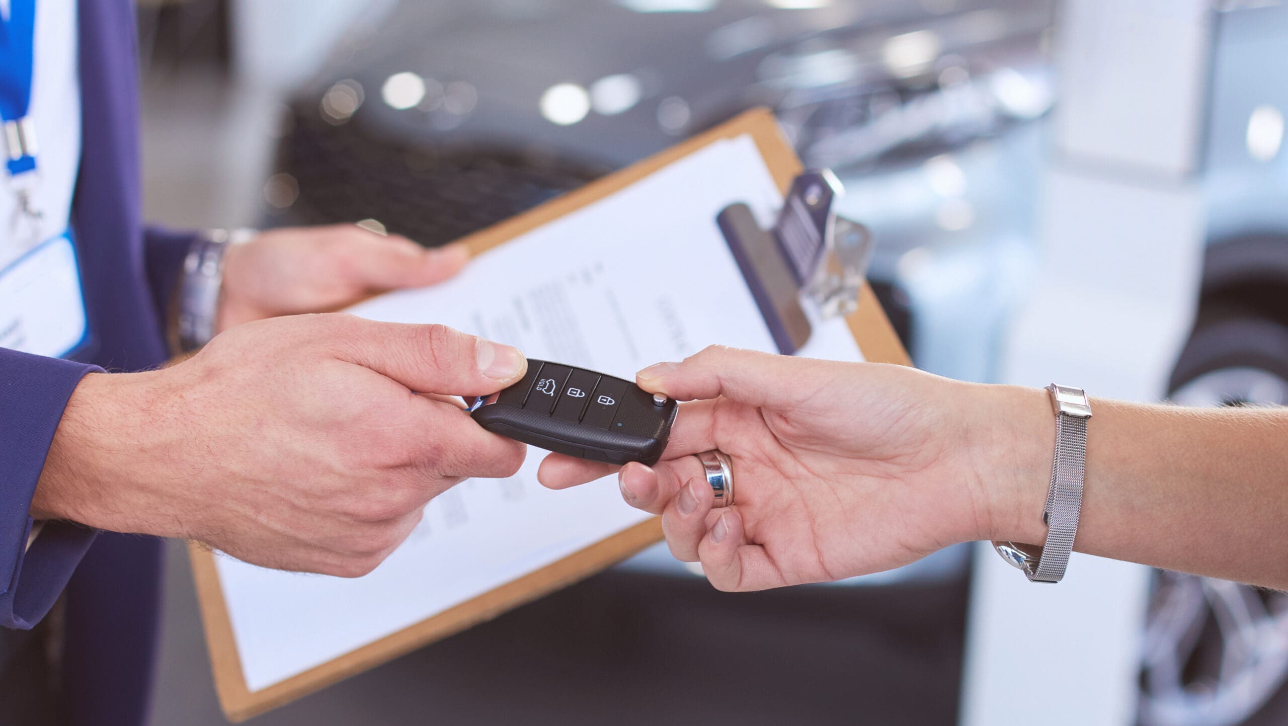 Car salesman sells a car to happy customer in car dealership and hands over the keys Life warranty 2